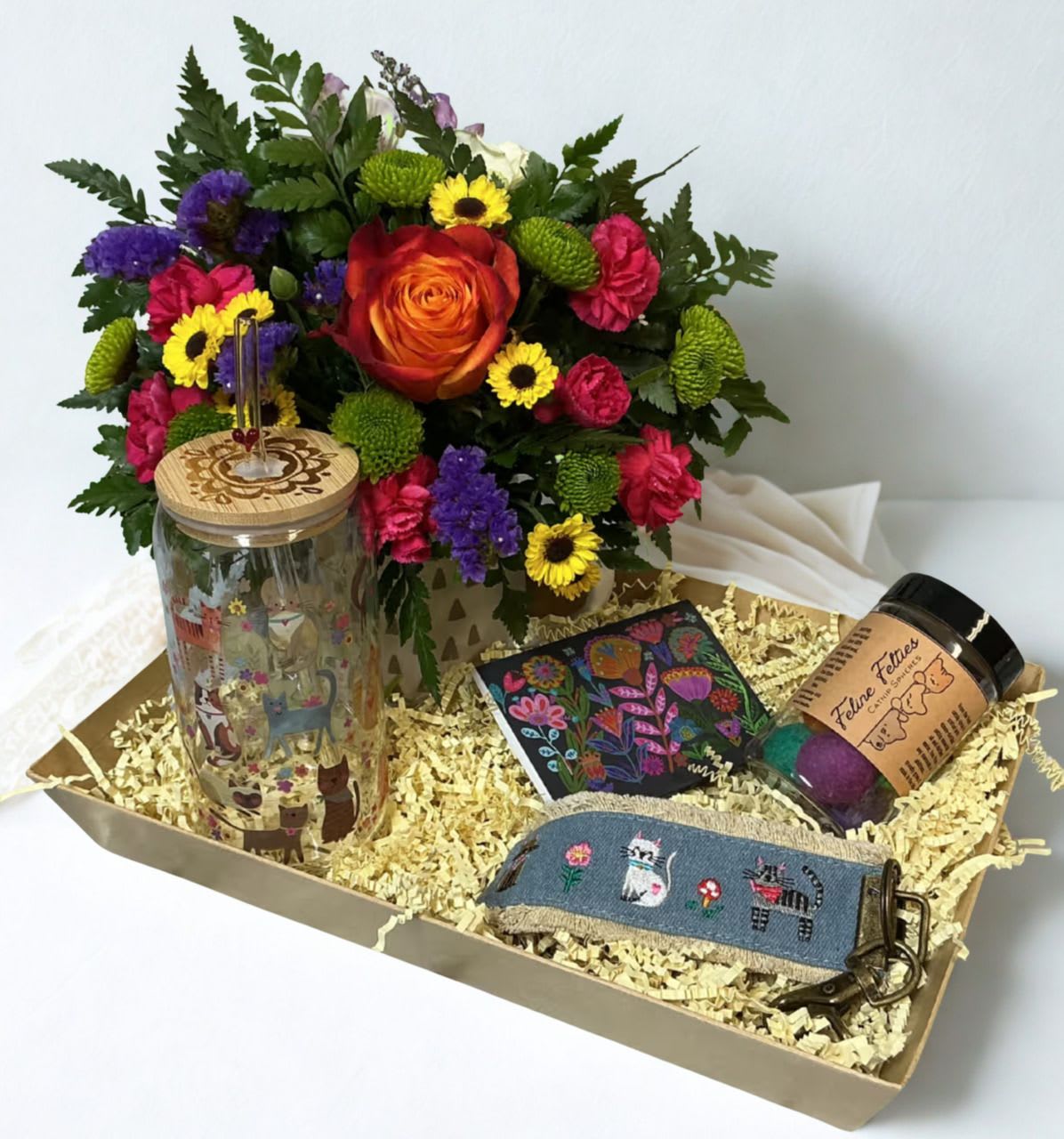 Purrs &amp; Petals Giftbox - Celebrate the love of a Cat Mom this Mother’s Day with the Purrs &amp; Petals Gift Box   This curated set features a beautiful fresh floral arrangement in a keepsake mug, a cat-themed tumbler for cozy sips, a cute cat keychain, and a set of Feline Felties catnip-infused felt spheres—perfect for keeping her feline friend happily entertained. To top it off, we’ve included a purse sized pack of lint/fur remover sheets—because cat hair is part of the love.  Thoughtful, practical, and full of personality, it’s the perfect gift for moms who adore their cats.