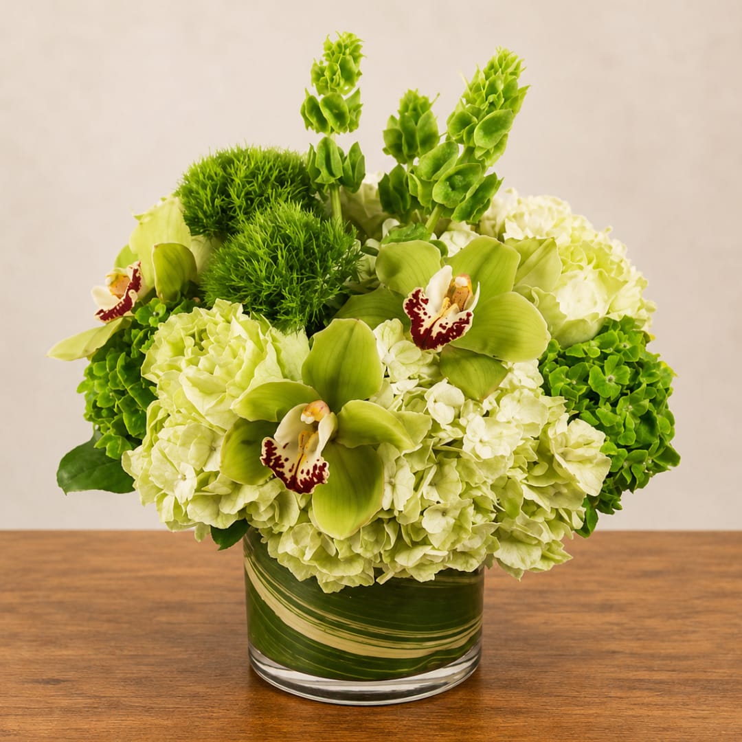 Green and white floral arrangement in a glass vase