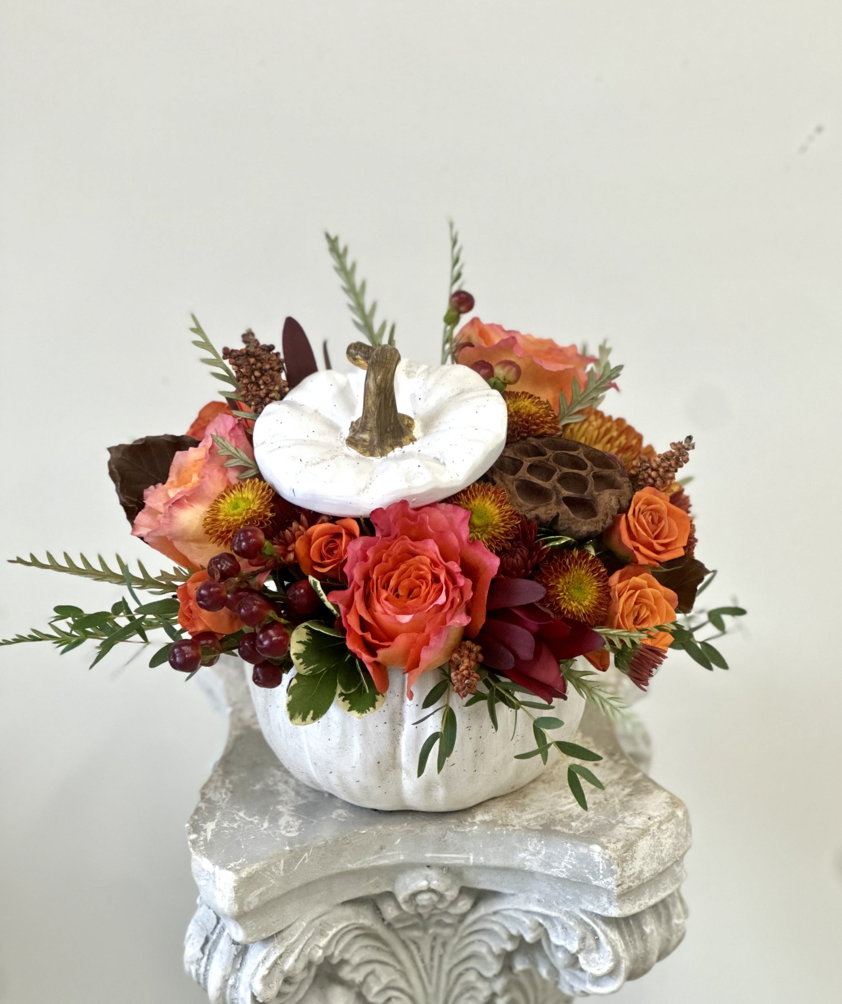Seasonal Delight by Westford Florist Art by Veny - Elevate your home decor with Seasonal Delight, a breathtaking floral arrangement by Westford Florist Art by Veny. This exquisite centerpiece combines the enchanting hues of pristine orange roses and spray roses, delicate lotus pods, burgundy hypericum berries, soft poms with the striking contrast of fall accents. All are artfully presented within an elegant white pumpkin, featuring a whimsical cut-off top that invites curiosity and charm into any space. Perfect for seasonal gatherings or as a sophisticated touch to your everyday ambiance, this arrangement captures nature's beauty in its most artistic form. Transform your environment and make every occasion memorable with this stunning piece.