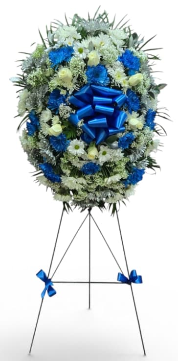 Blue and white funeral wreath on a standing easel with a large blue bow
