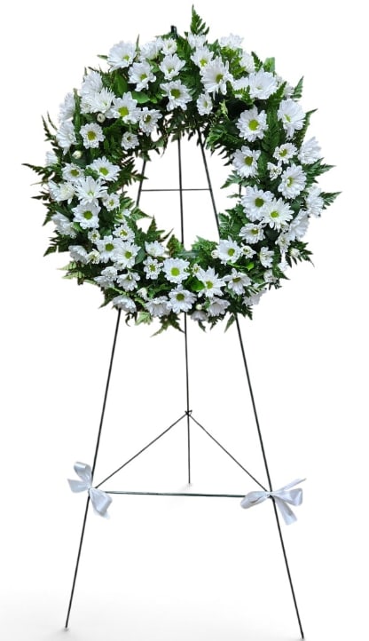 White daisy wreath on a standing easel with white ribbon bows