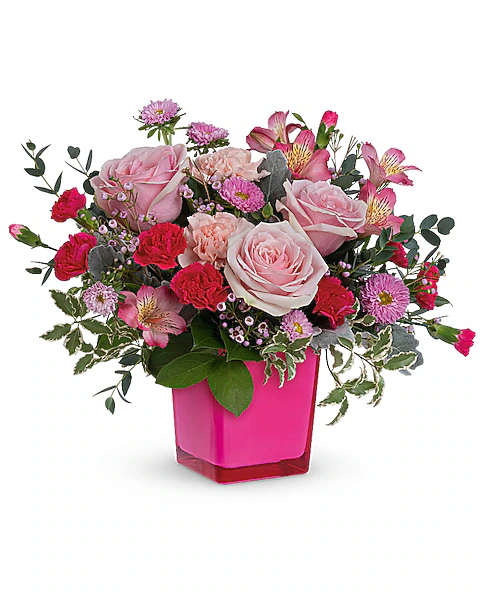 Pink roses and mixed blooms arranged in a bright pink vase