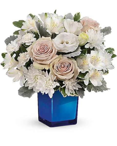White and blush flowers arranged in a blue glass vase
