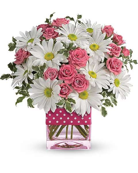 Pink roses and white daisies in a clear square vase with a polka-dot wrap