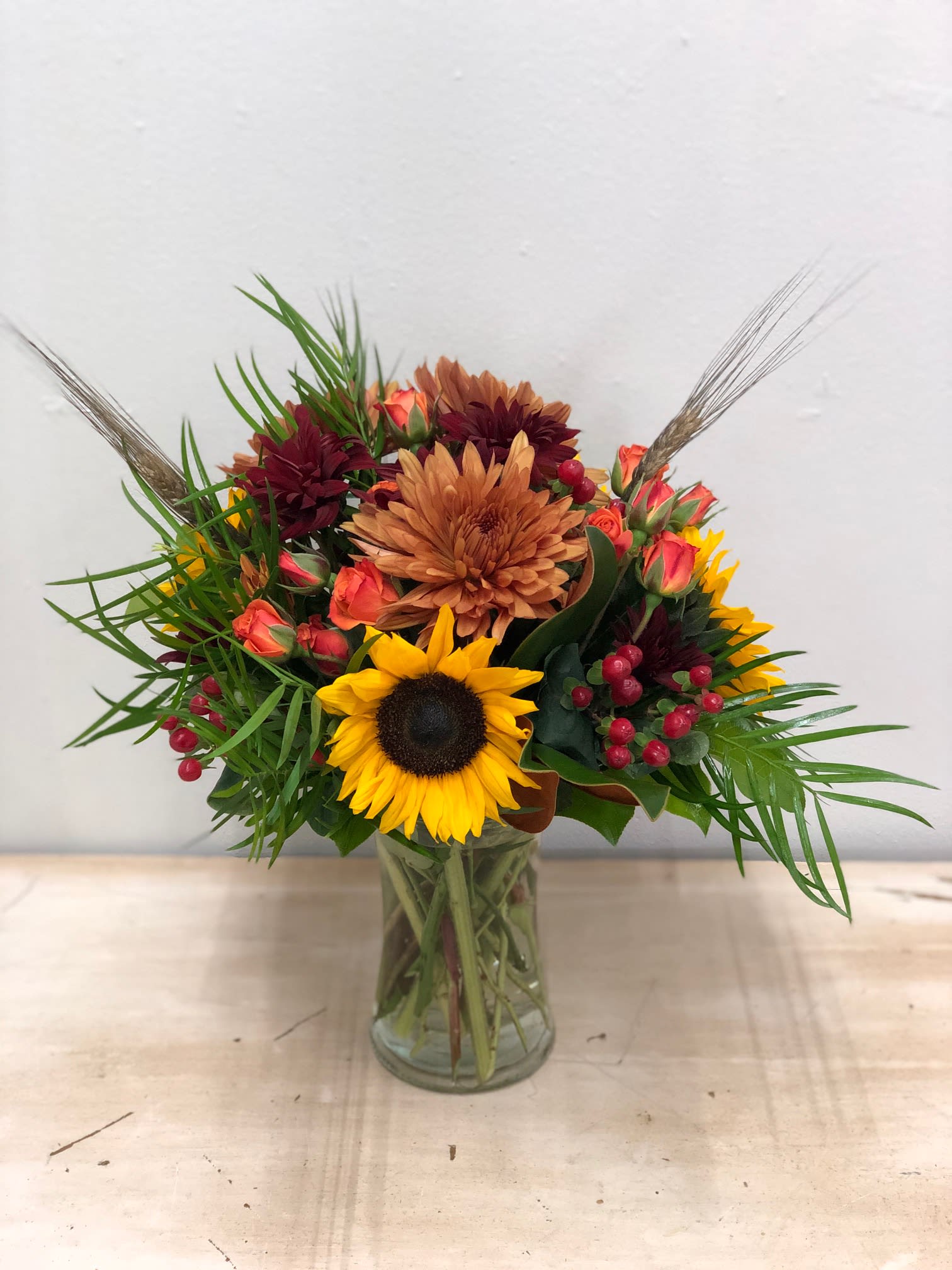 Feels Like Autumn Bouquet - Wonderful flowers arranged together to give you all the autumn feels! Mixture of spray roses, sunflowers, mums, hypericum berries, etc..   Flowers and colors may be substituted depending on availability and season.  