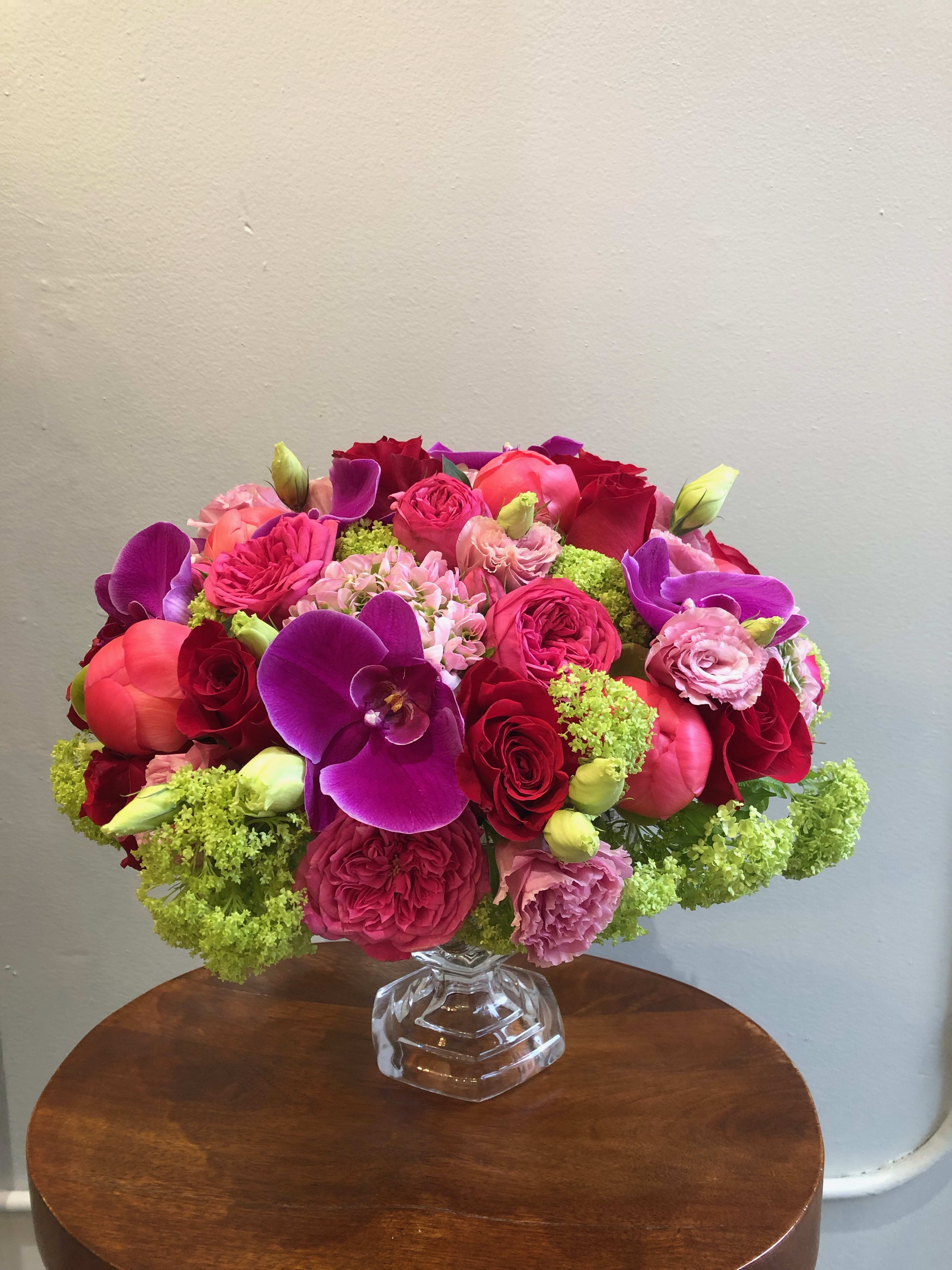 Bright mixed bouquet in a clear glass vase with purple orchids and pink roses