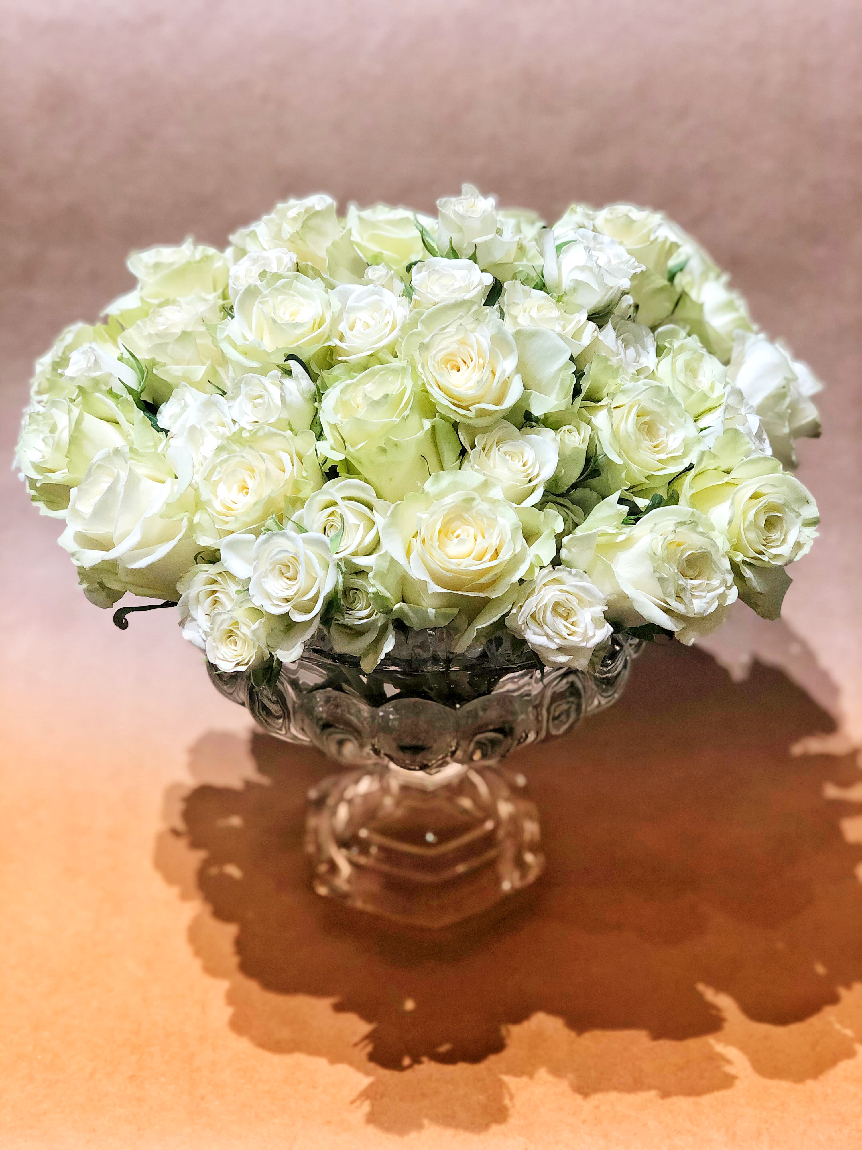White rose bouquet in a clear glass pedestal vase