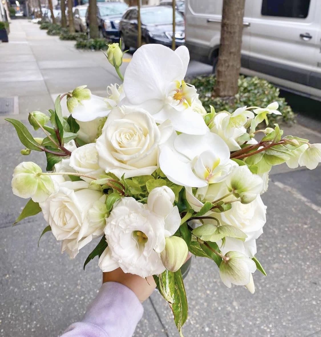 White rose and orchid bouquet held outdoors