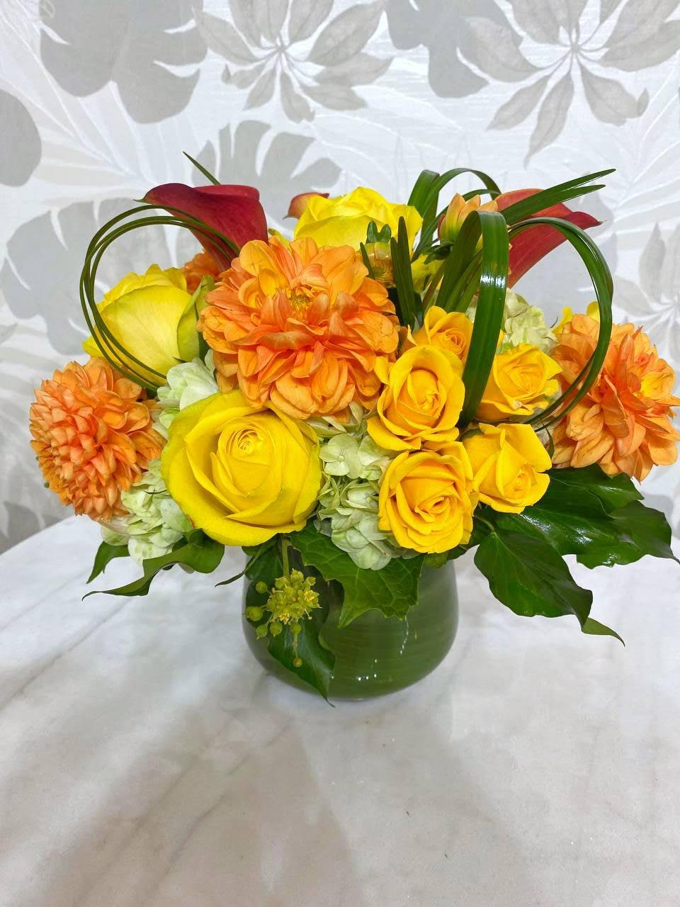 Yellow roses and orange dahlias in a green vase