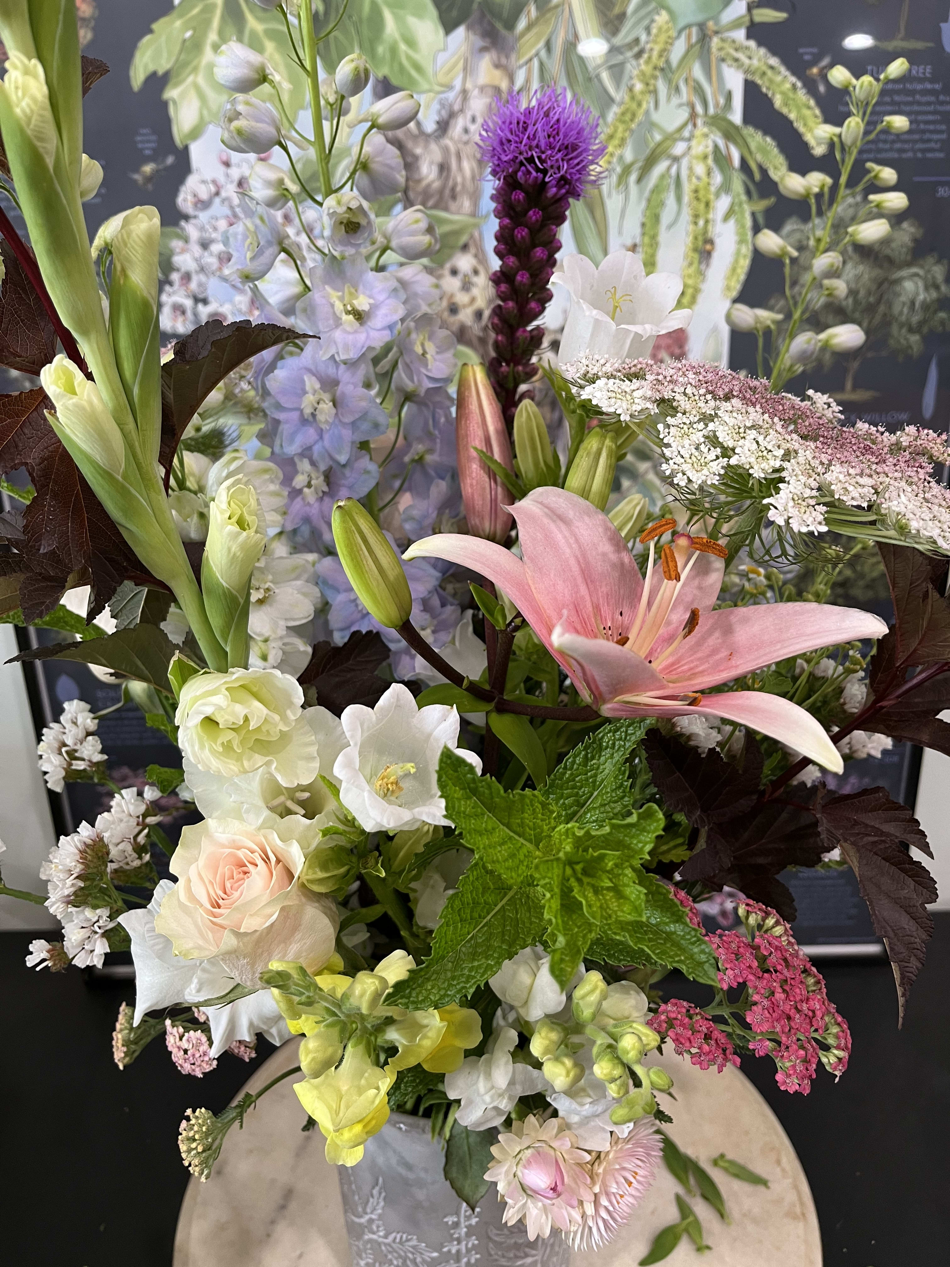 Mixed bouquet with pink lily, roses, and pale blue flowers in a vase