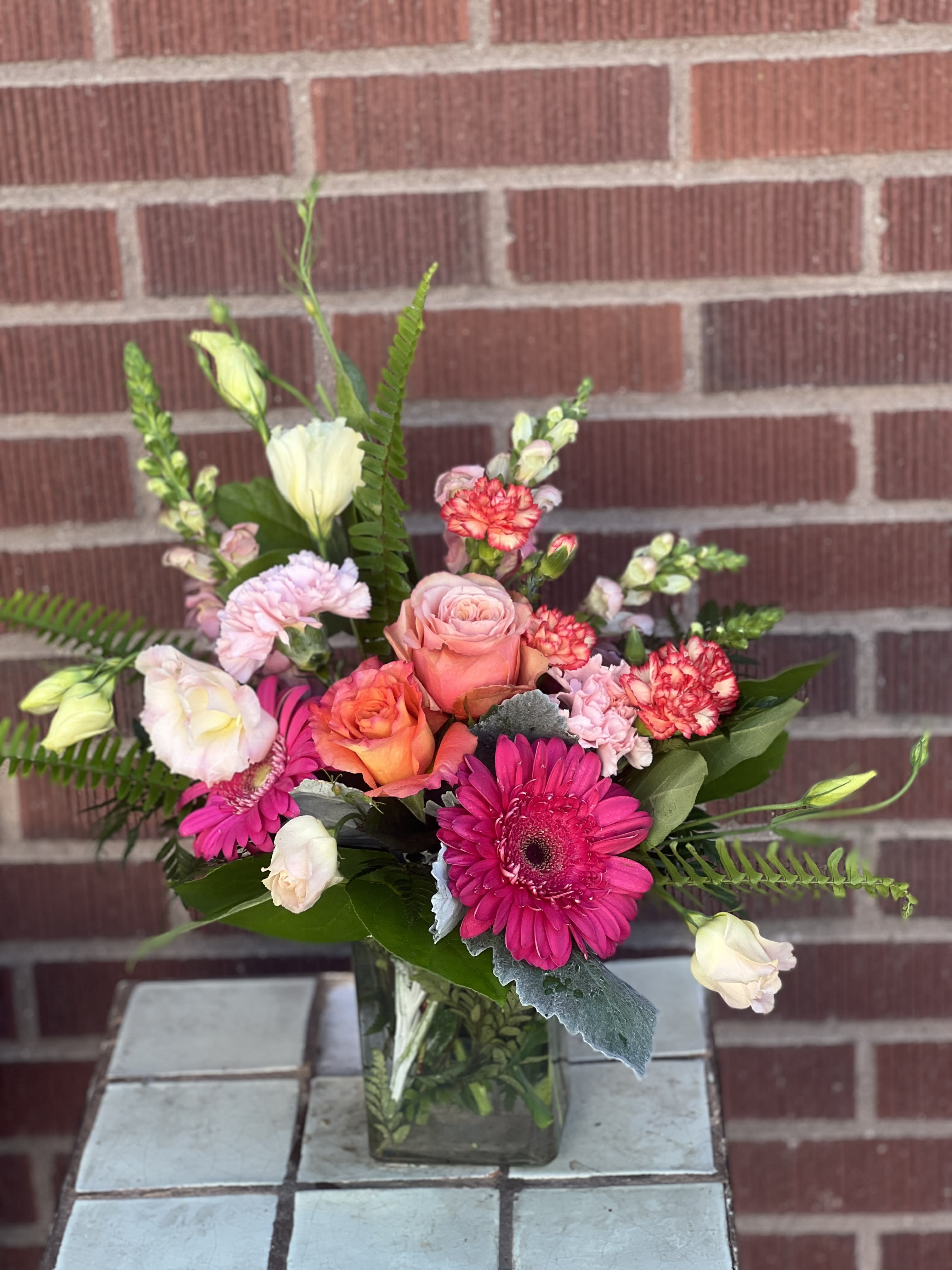 Mixed pink and peach bouquet in a square glass vase