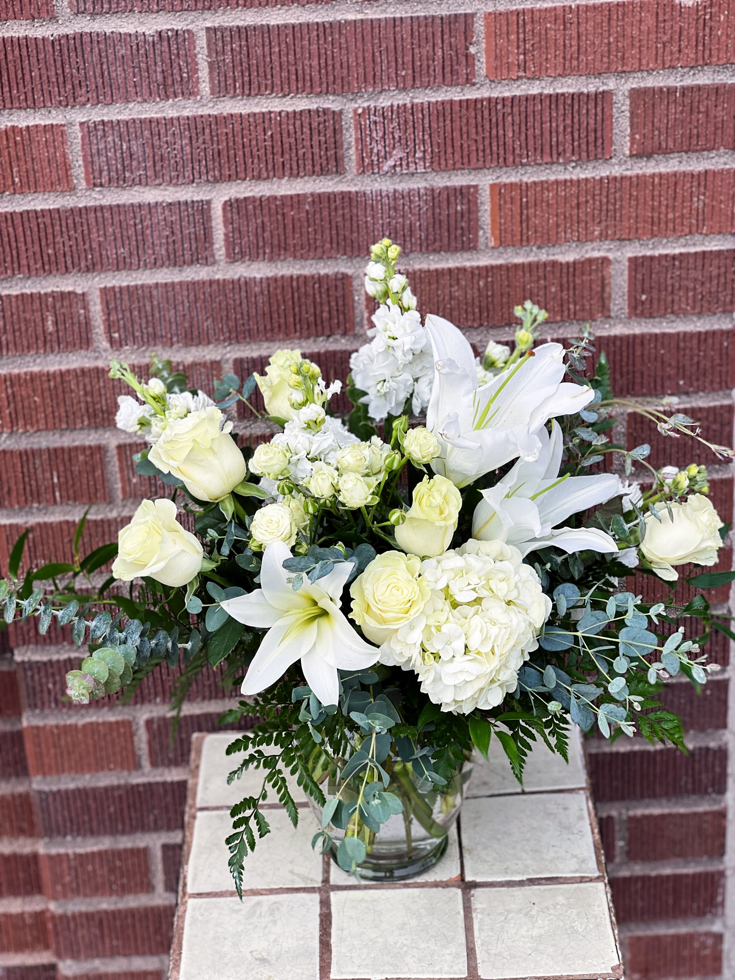 White roses and lilies arranged in a glass vase