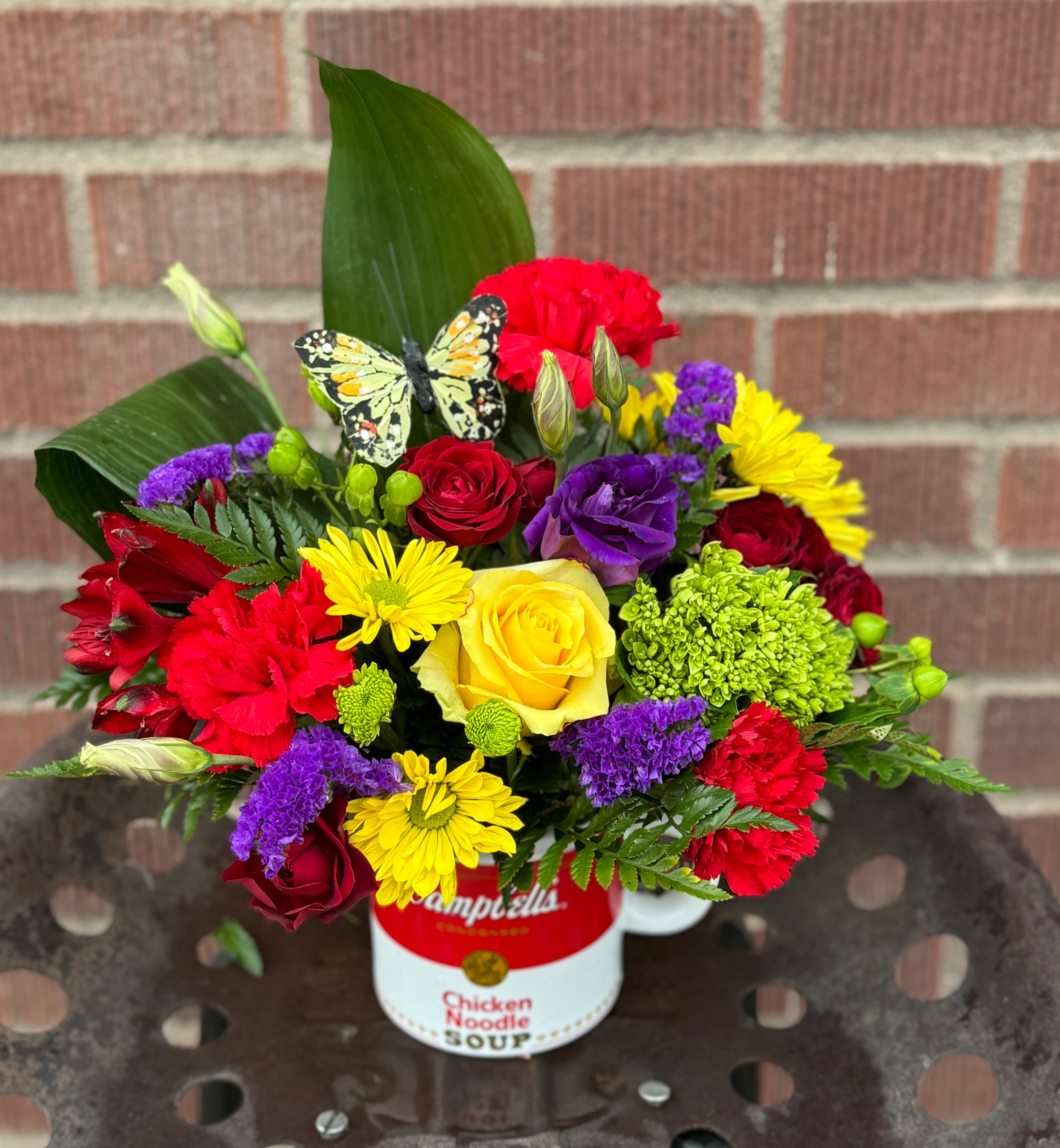 Colorful mixed bouquet in a soup can with a butterfly decoration