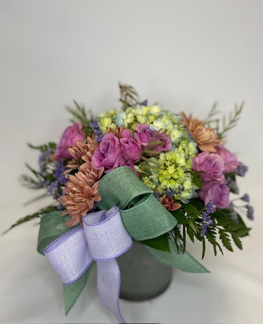 Bouquet of pink, purple, and yellow flowers with a lavender ribbon in a vase