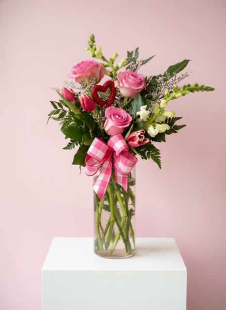 Pink roses and tulips in a glass vase with a checkered bow