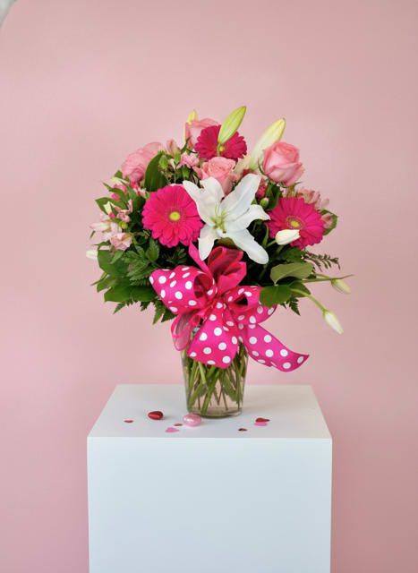 Pink and white bouquet in a glass vase with a polka-dot ribbon