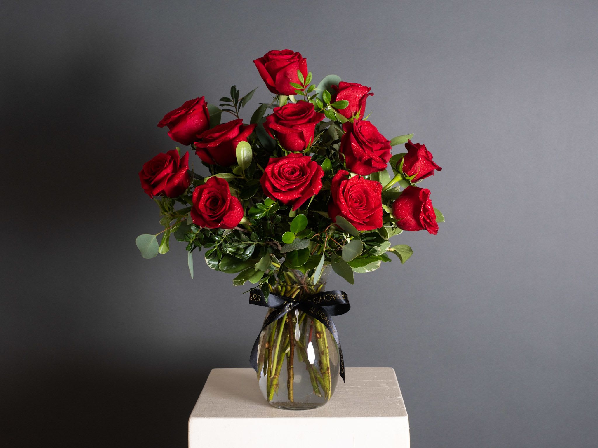 Bouquet of red roses in a clear glass vase with a black ribbon