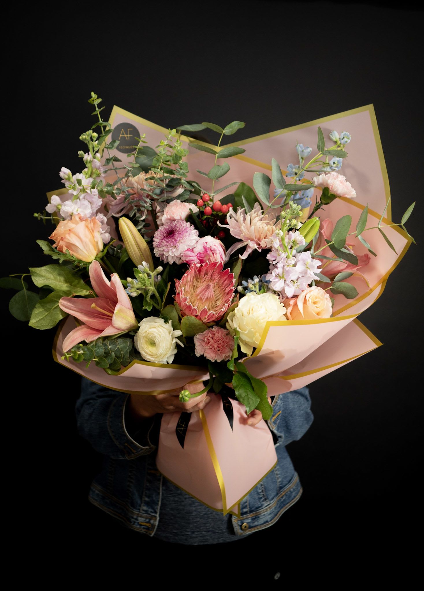 Mixed bouquet of pink, peach, and white flowers wrapped in pink paper