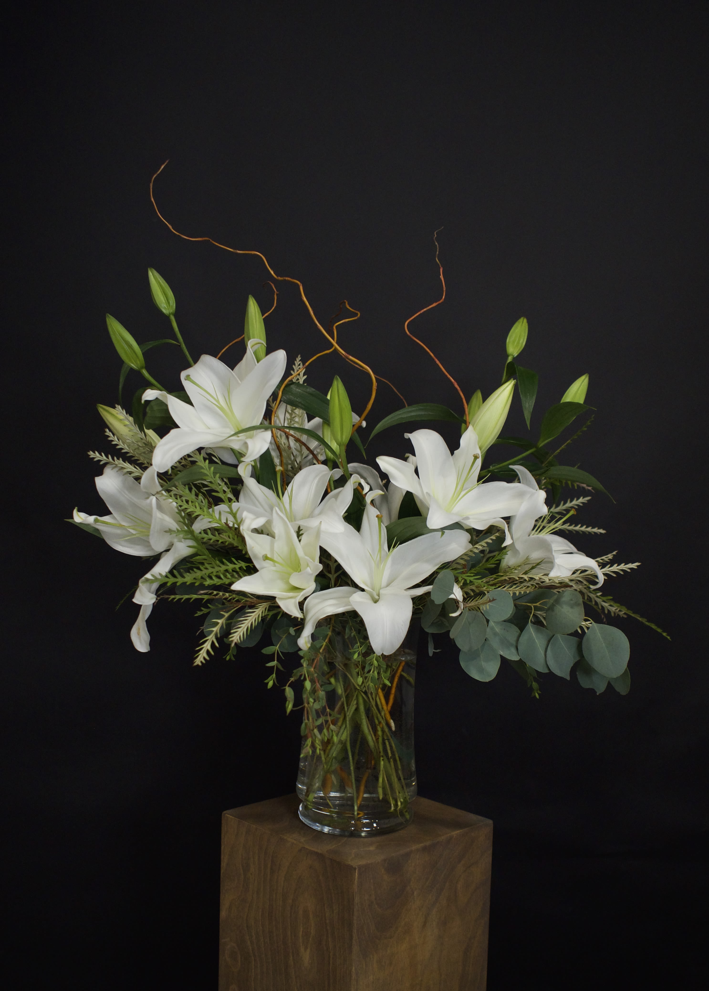 Elegant lily vase arrangement - A timeless vase arrangement featuring fragrant lilies accented with fresh greenery and decorative curly willow. As the lilies open, this design becomes even more stunning, creating a beautiful display that can be enjoyed for days.  Available with either white or pink lilies. If you would prefer pink lilies, please let us know in the "Notes for the Florist / Special Instructions" box during checkout.  IMPORTANT : Lilies are highly toxic to cats and should never be sent to homes with cats. Due to their strong fragrance and pollen, lilies may also not be suitable for recipients with flower allergies or sensitivities.