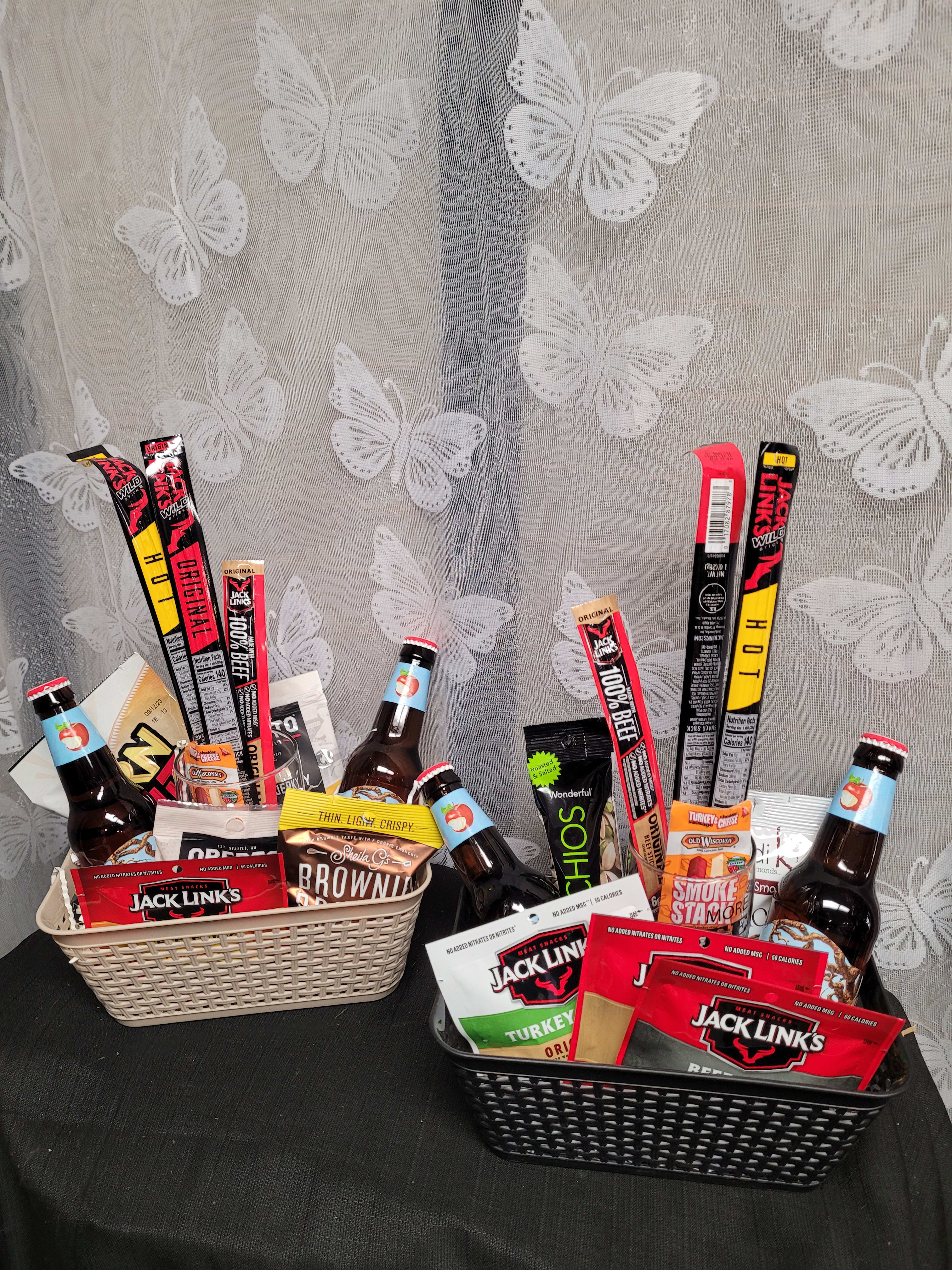 Two gift baskets filled with snacks and bottled drinks on a table
