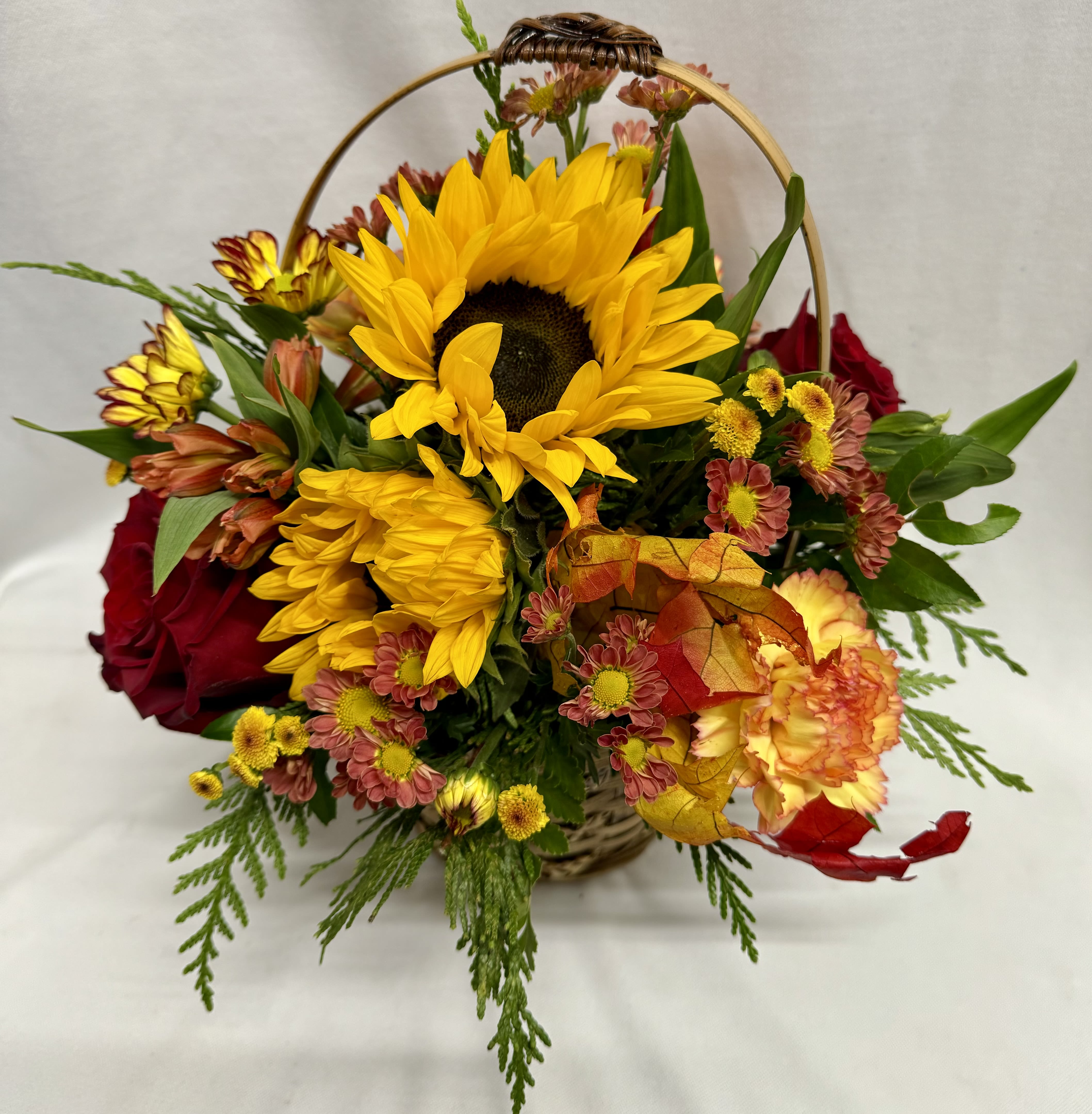 Basket arrangement with sunflowers, red roses, and mixed fall flowers