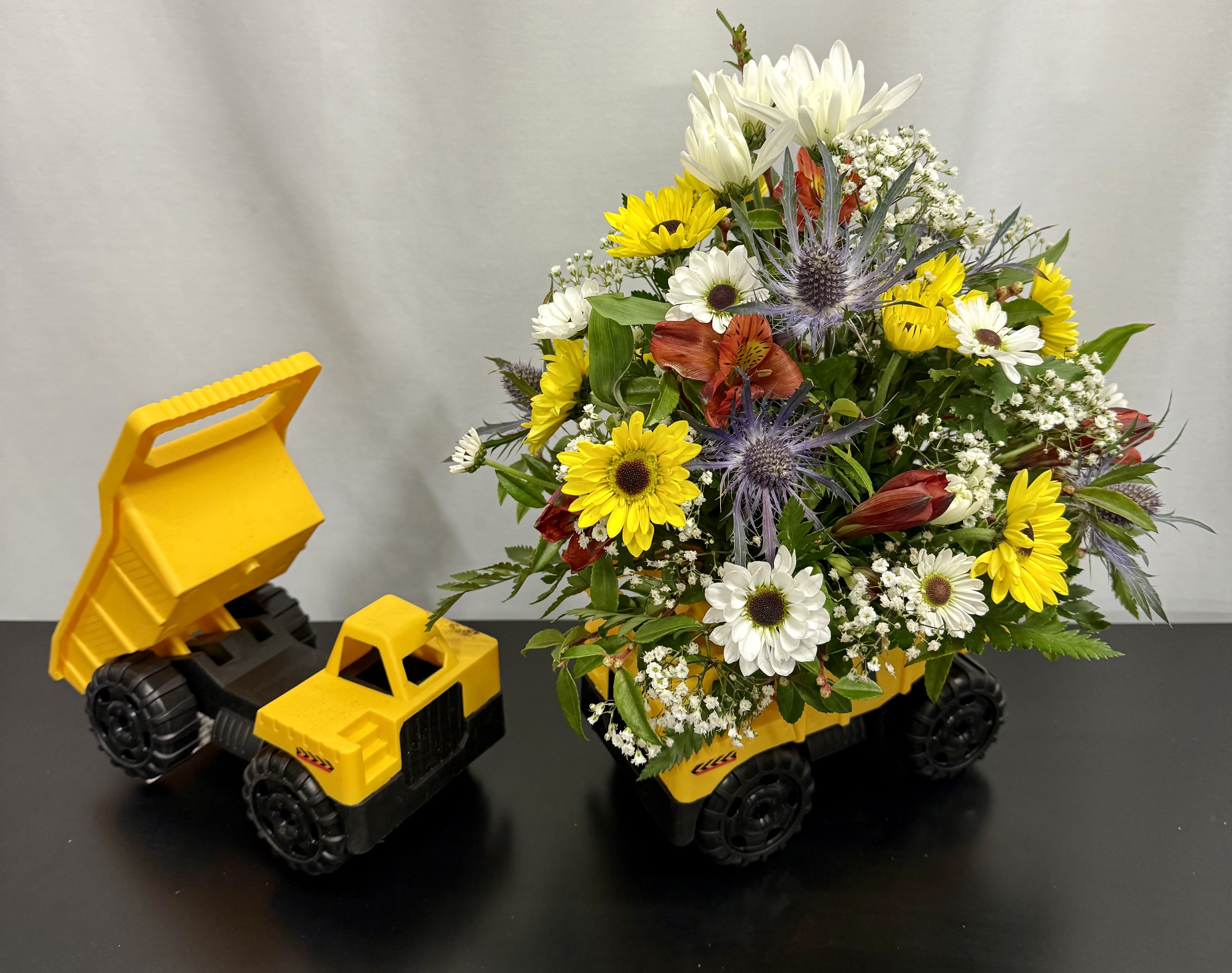 Bouquet in a yellow toy dump truck with white and yellow flowers