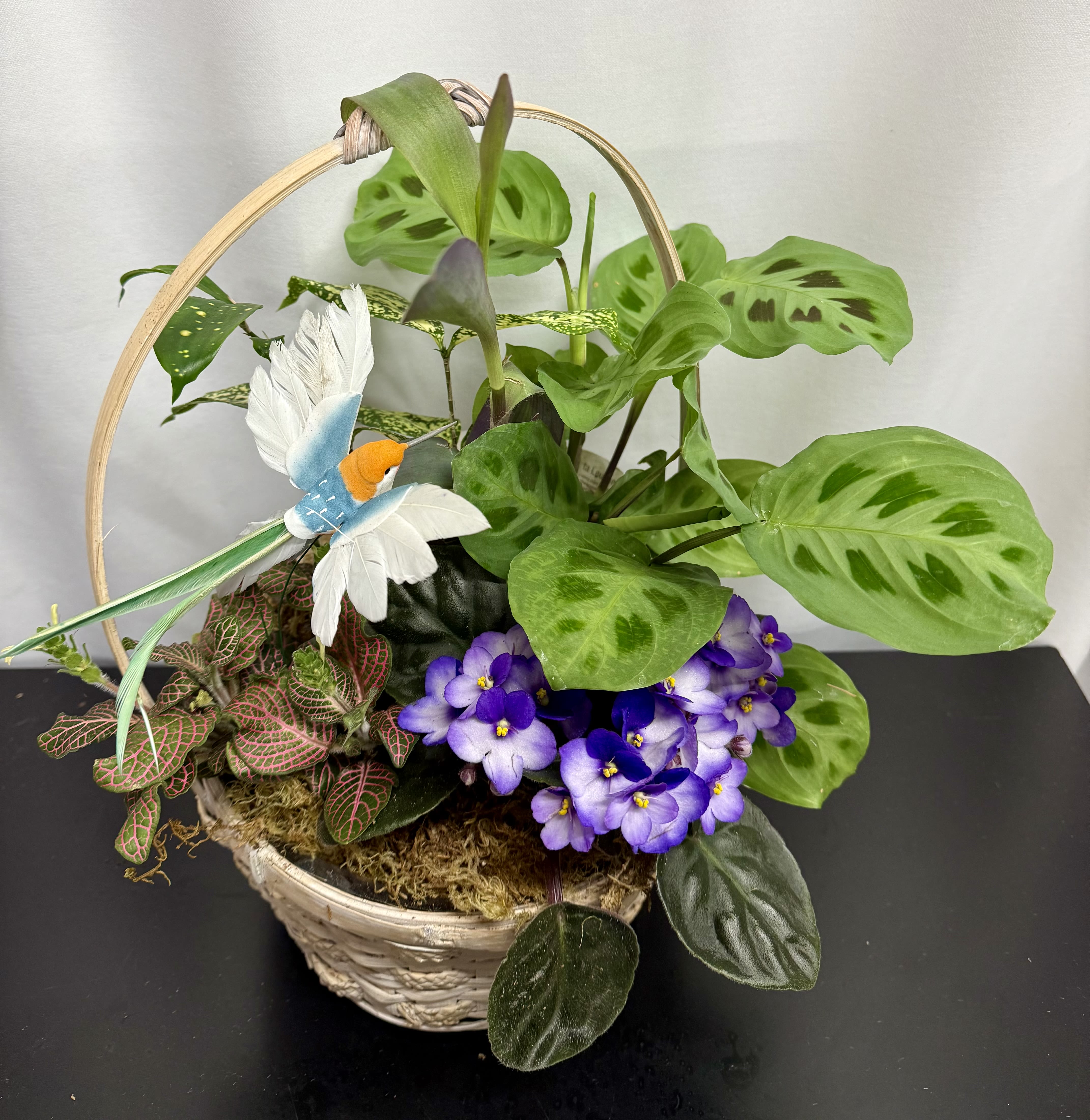 Basket planter with green foliage, purple flowers, and a decorative bird
