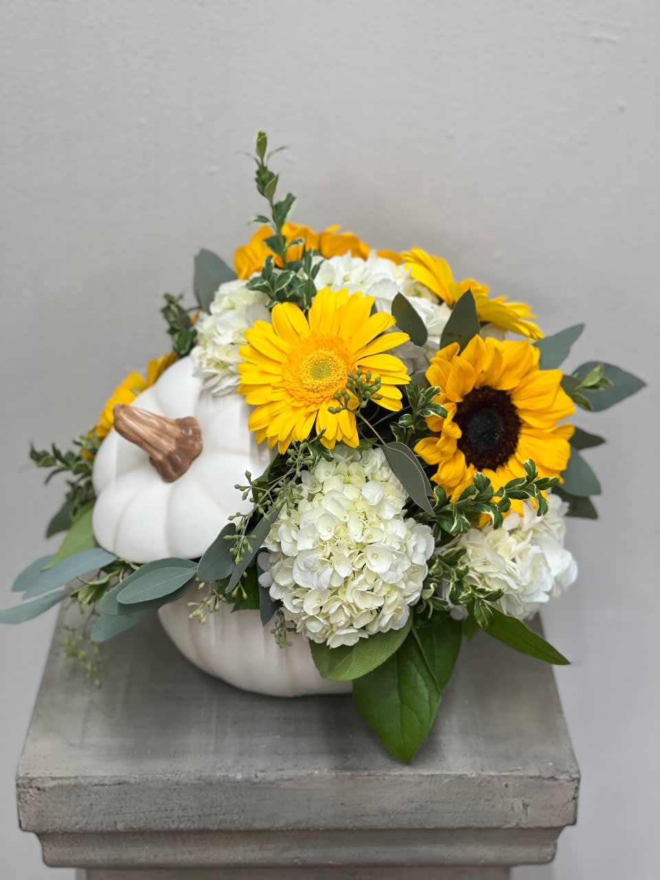 White pumpkin arrangement with yellow sunflowers and white hydrangeas