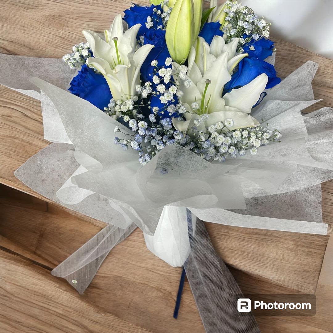 Bouquet of white lilies and blue roses wrapped in white paper