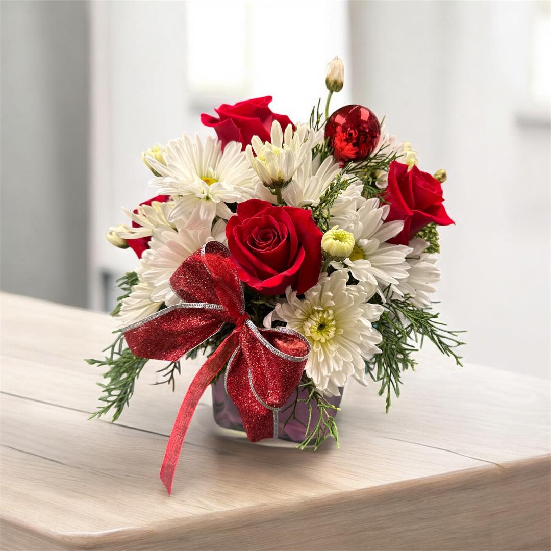 Red roses and white daisies in a small glass vase with a red bow