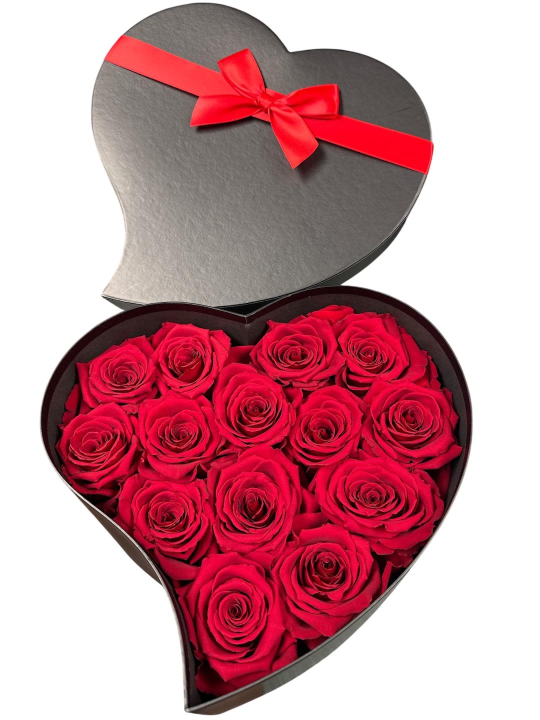 Heart-shaped box filled with red roses and tied with a red ribbon
