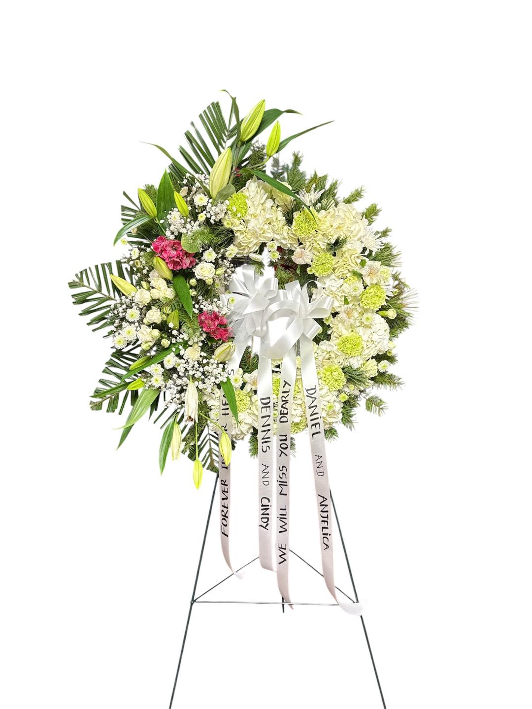 Standing funeral wreath of white and green flowers with ribbon streamers