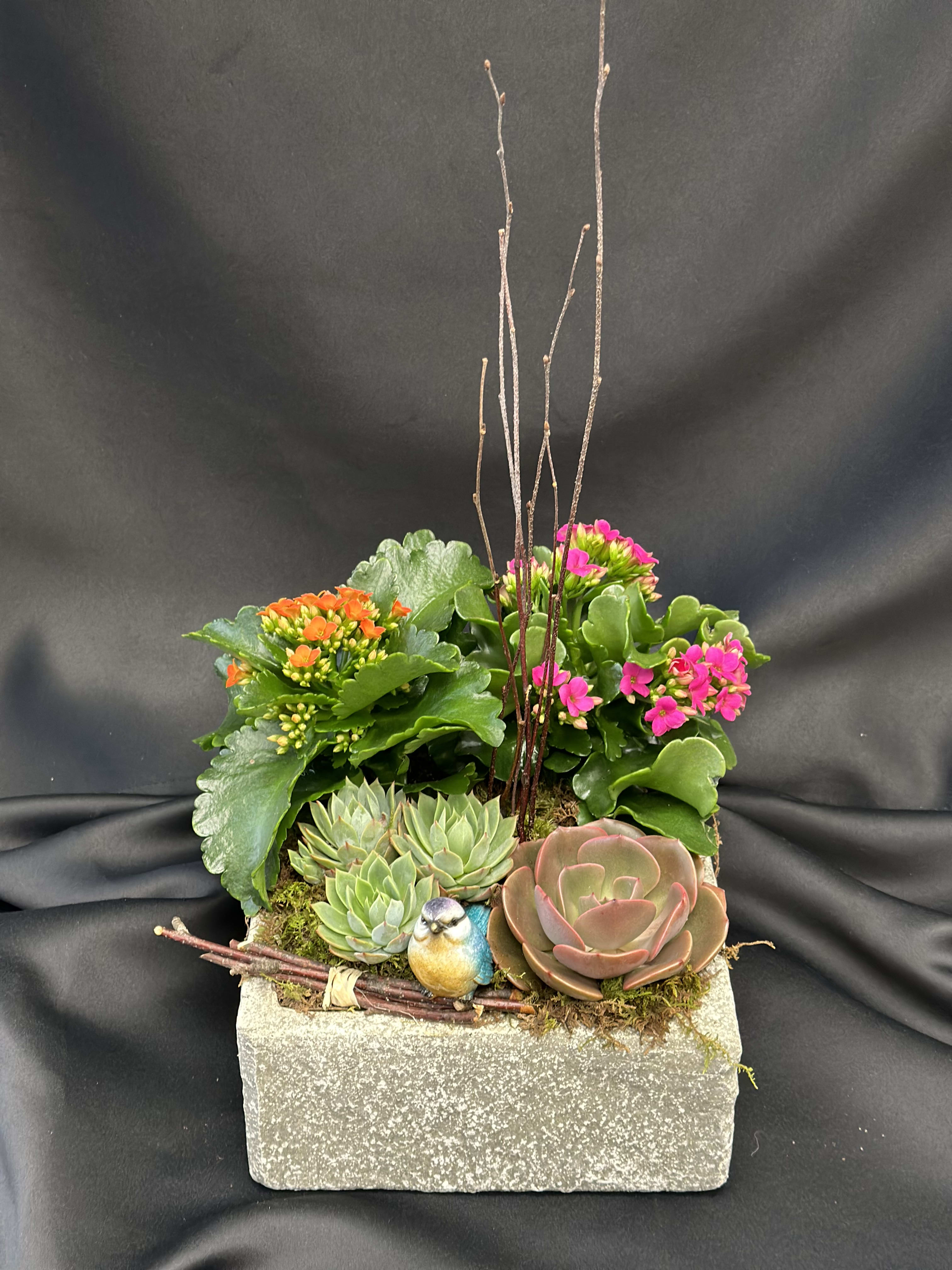 Succulent planter with pink and orange blooms in a rectangular stone container