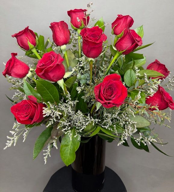 Bouquet of red roses with white filler in a black vase