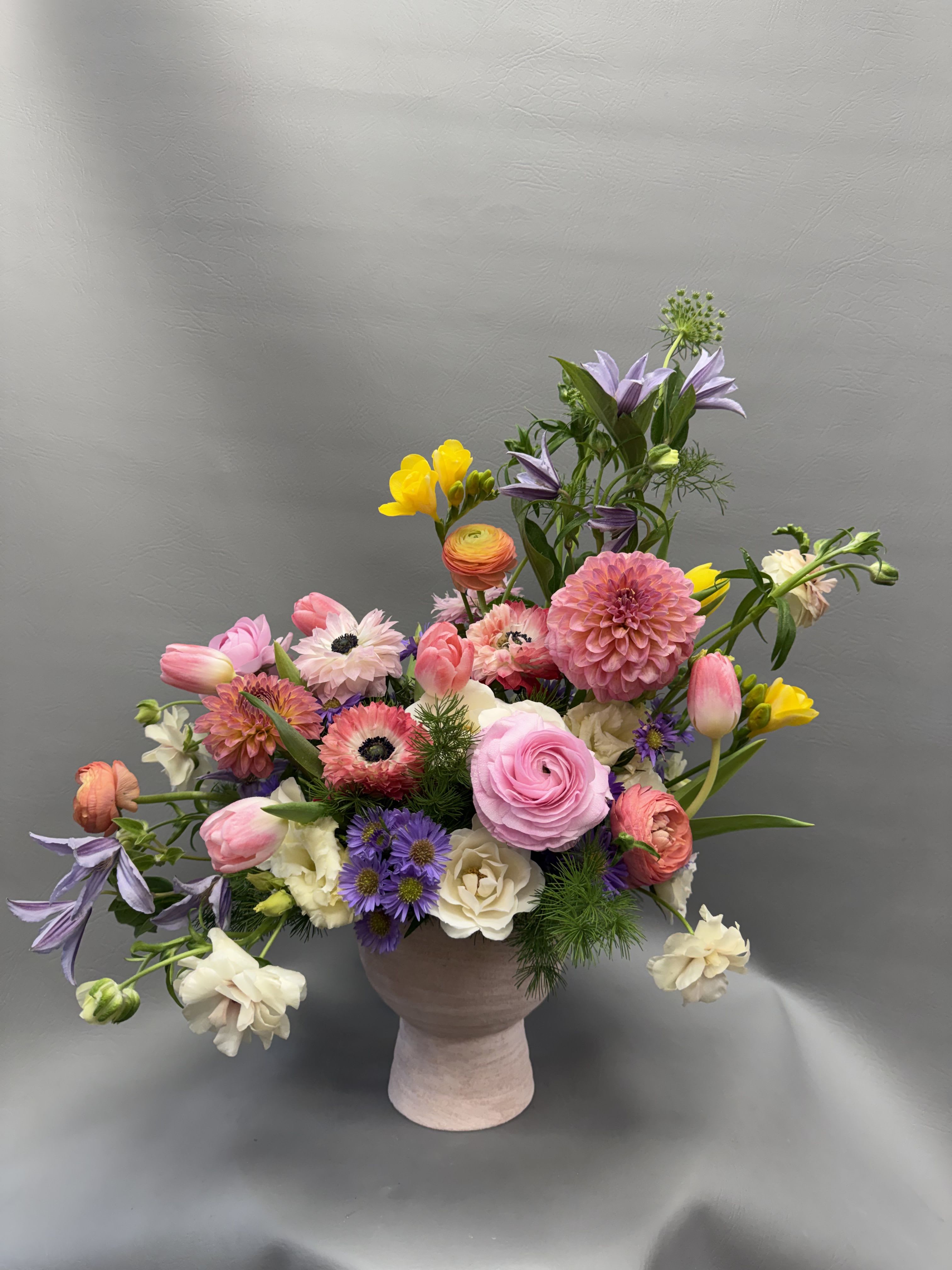 Mixed bouquet in a pink vase with pink, purple, white, and yellow flowers