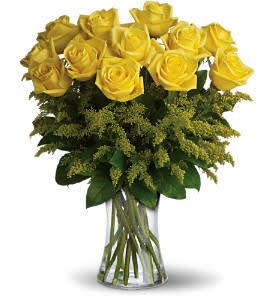 Arrangement of yellow roses with feathery green filler in a clear glass vase