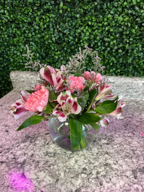 Pink and white flowers arranged in a clear glass bowl vase