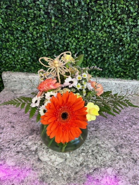 Orange gerbera daisy arrangement in a glass vase with small white flowers