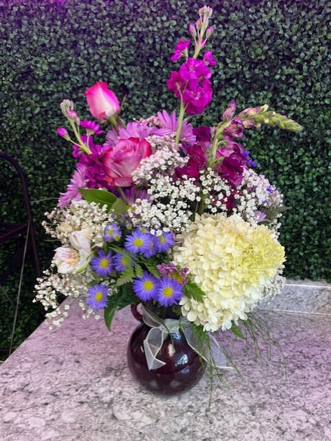 Mixed bouquet in a dark glass vase with pink, purple, and white flowers