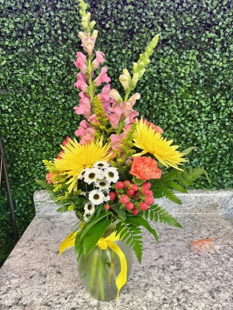 Mixed bouquet in a glass vase with yellow, pink, white, and coral flowers