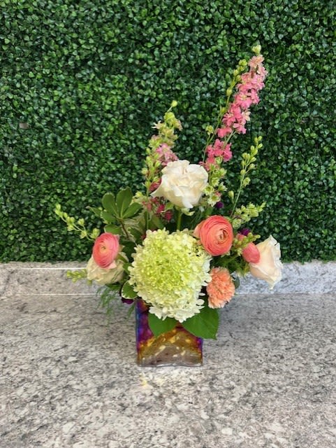 Mixed bouquet in a square glass vase with pink, white, and green blooms