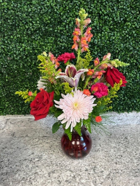 Mixed bouquet with red roses, a white daisy, and lilies in a glass vase