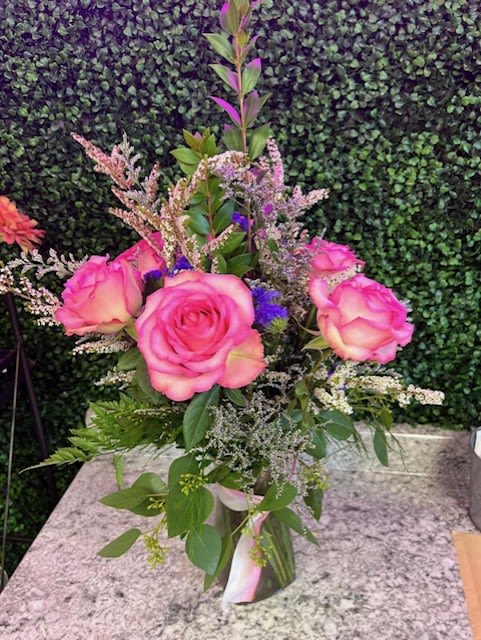 Pink roses arranged in a clear vase with mixed filler flowers
