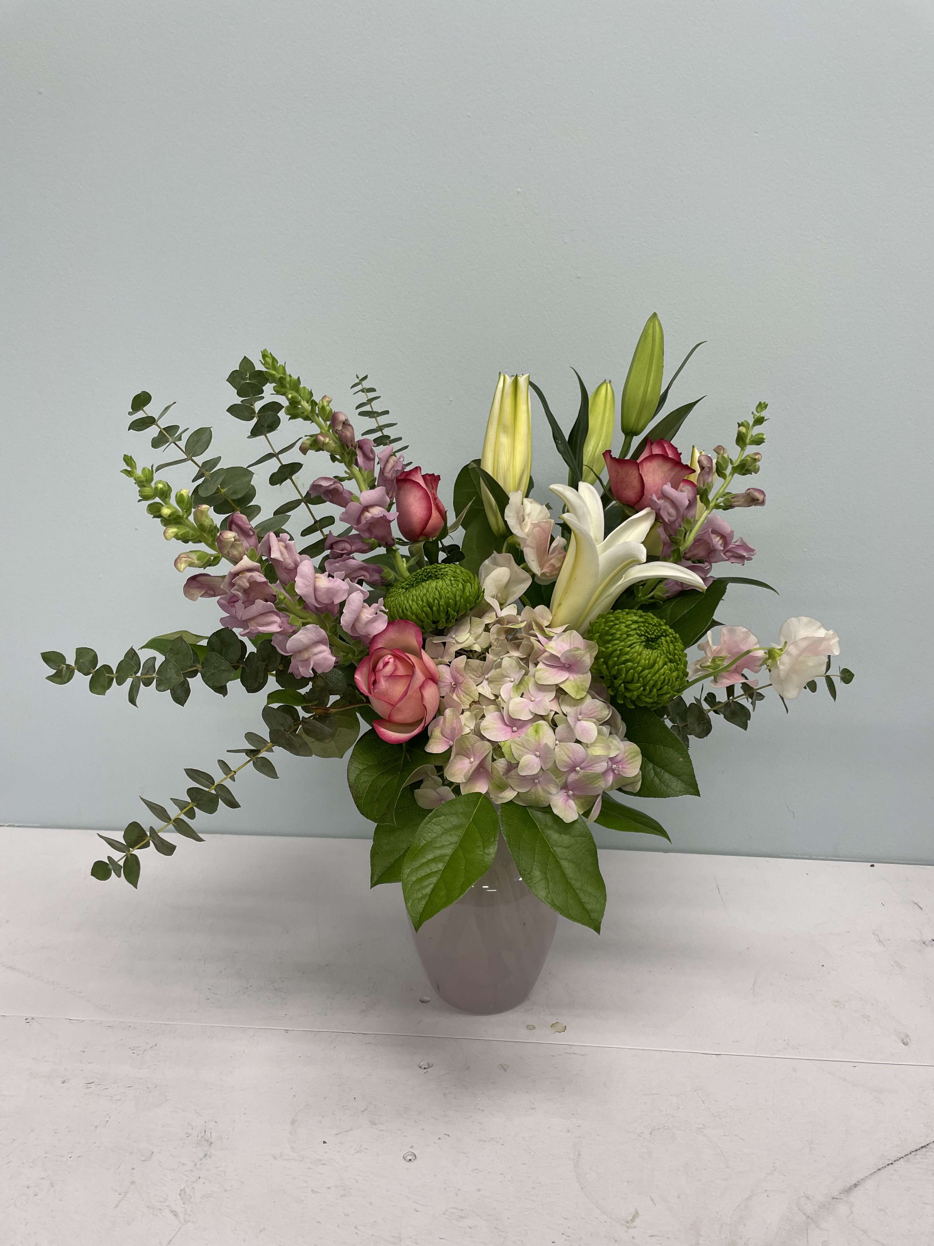 Mixed bouquet with pink roses, lilies, hydrangea, and green mums in a vase