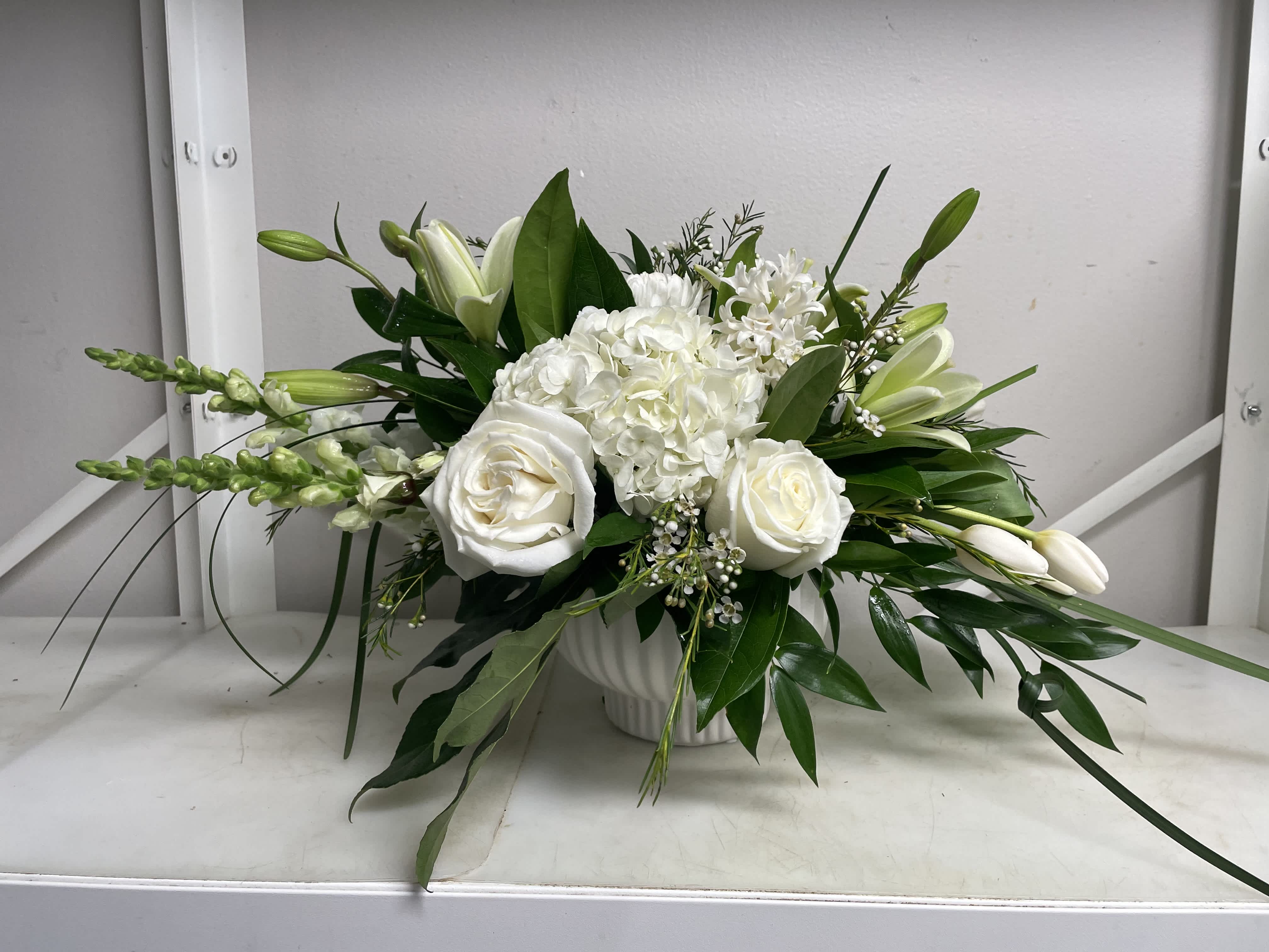 White roses and lilies arranged in a white vase