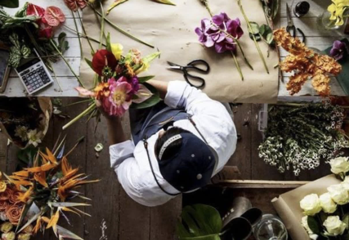 Florist arranging colorful flowers on a worktable with scissors and paper