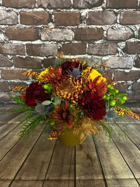 Autumn floral arrangement in a gold vase with burgundy and orange blooms