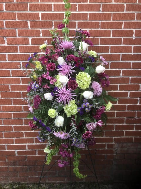 Large standing floral spray with purple, white, and green blooms