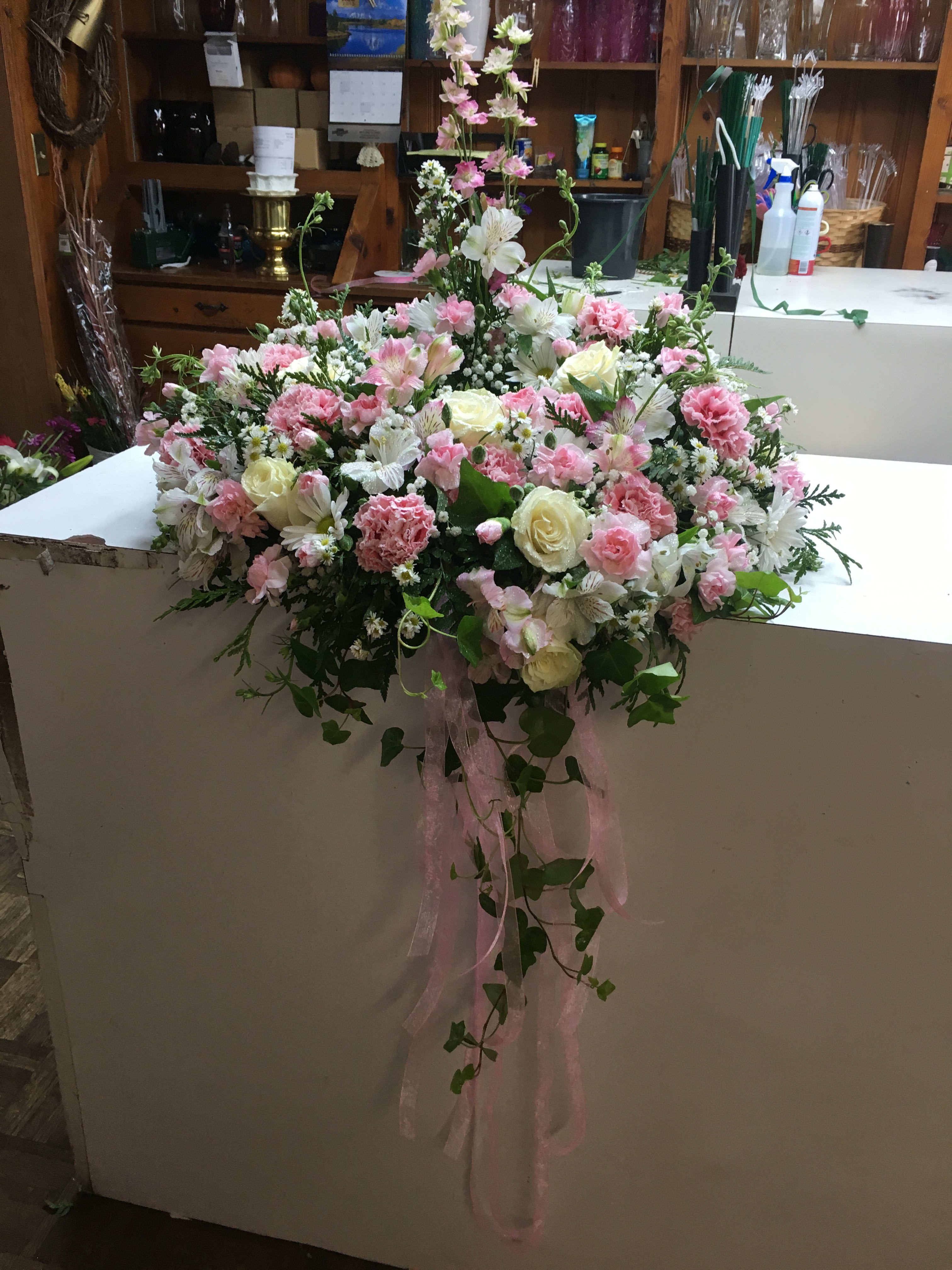 Large pink and white floral arrangement with trailing ribbon