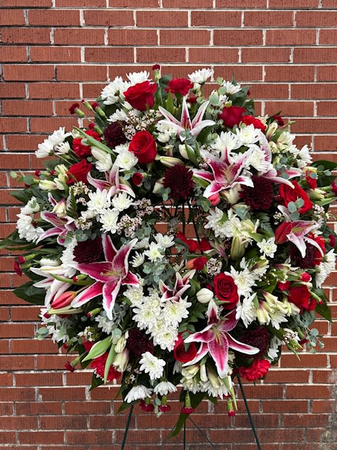 Large standing floral wreath with red, white, and pink blooms on an easel